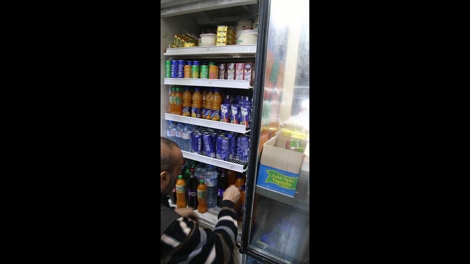 مستفيد يختار حاجاته من ثلاجة المشروبات في السوق